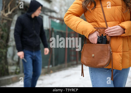 Frau, die Pistole aus der Tasche, um sich gegen Räuber zu schützen. Stockfoto