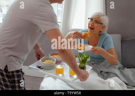 Schließen Portrait der Dame gehen, eine frisch gebackene Croissants zu essen Stockfoto
