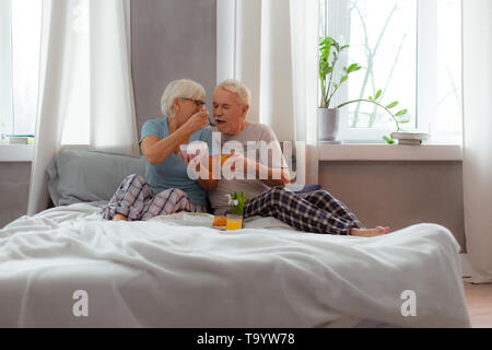 Liebevolle Frau ihrem Ehemann Fütterung mit Porridge mit einem Löffel Stockfoto