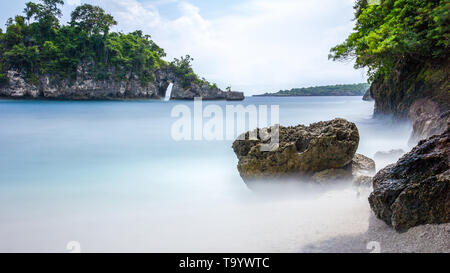 Lange Exposition von Felsen am Strand zwischen Wellen Stockfoto