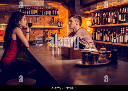 Frau in rotem Kleid zu sprechen Barkeeper und Trinken Stockfoto