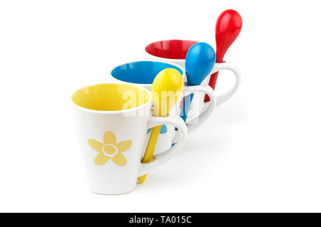 Bunte Tassen und Löffel auf weißem Hintergrund Stockfoto