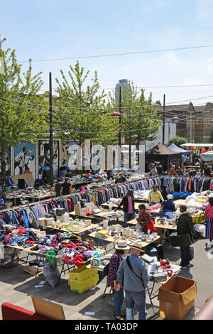 Open-air-Markt in Deptford, südöstlich von London, UK. Zeigt Racks von Kleidung und Tabellen mit inländischen Artikel zum Verkauf. Kunden surfen. Stockfoto