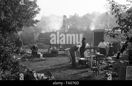 Bergung waren nach einem strohgedeckten Haus Feuer c 1973 im Dorchester, Dorset. Hinweis Die noch glimmenden Gebäude wie Feuerwehrleute machen was sicher bleibt. Foto von Tony Henshaw Stockfoto