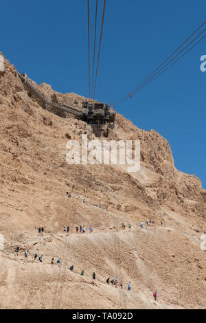 Israel, historischen Masada aka Massada. Seilbahn auf den Gipfel des Masada. Touristen wandern bis zum Gipfel auf der Schlange Weg in der Ferne. Stockfoto