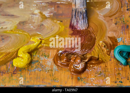 Kreative Bild, Artist's Palette mit Öl Farben und Pinsel, Nahaufnahme, alte hölzerne Palette, Farben und Lacke in verschiedenen Farben, close-up Pinsel des Künstlers Stockfoto