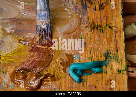 Kreative Bild, Artist's Palette mit Öl Farben und Pinsel, Nahaufnahme, alte hölzerne Palette, Farben und Lacke in verschiedenen Farben, close-up Pinsel des Künstlers Stockfoto