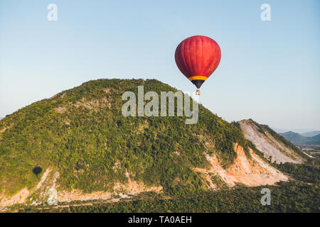 Red Hot-Ballons fliegen über die Berge und grüne Reisfelder in Vang Vieng, Laos Stockfoto