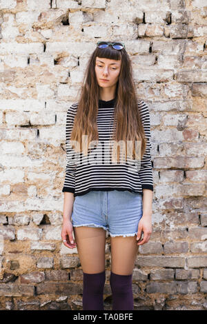 Junge Frau stand vor Backsteinmauer Stockfoto