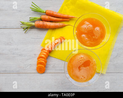 Gläser Karottensaft und frische Karotten auf Holzbrett Stockfoto