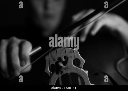 Ein junger Cellist Praktiken intensiv auf seinem Cello, gesehen von der Brücke und Bug Seite Stockfoto