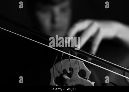 Ein junger Cellist Praktiken intensiv auf seinem Cello, gesehen von der Brücke und Bug Seite Stockfoto