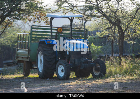 Hluhluwe, Südafrika - 14. Mai 2019: Eine blaue Traktor mit Anhänger atttached. Stockfoto