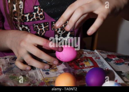 Junges Mädchen, 13, streuen Glitzer auf Ostereier in der Vorbereitung für die Osterfeiertage. Stockfoto