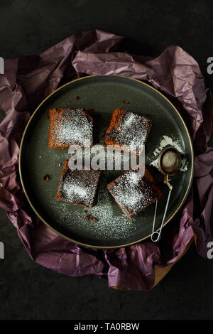 Leckeren, gesunden veganen Feucht milchfrei dark chocolate brownies Dessert oder quadratische Schwamm Kuchen ohne Eier gekocht und mit Puderzucker eingerichtet Stockfoto