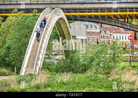 Nijmegen, Niederlande, 25. April 2019: Fußgänger klettern die Schritte des Ooypoort Bogenbrücke, mit Riverfront der Stadt und der alten Waal Brücke Stockfoto