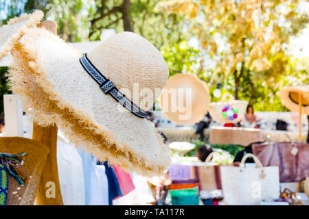 Nahaufnahme von einigen verschiedenen Mode Accessoires und Kleidung auf Verkauf in einem Street Market, Markieren einige Strohhüte im Vordergrund. Stockfoto
