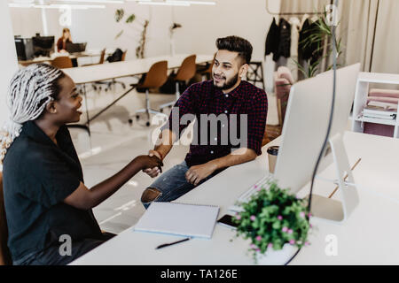 Freundlich lächelnden indischer Geschäftsmann und afrikanischen Geschäftsfrau handshaking über das Büro Schreibtisch nach angenehmes Gespräch und effektive Verhandlungen, gute rel Stockfoto