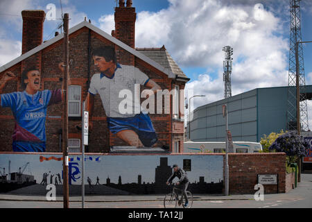 Ein Mann radfahren Vergangenheit ein Wandgemälde des Künstlers Paul Curtis auf die giebelseite eines Hauses in Prenton, Wirral mit zwei Tranmere Rovers Spieler. Das Wandbild ist nur außerhalb des Stadion des Clubs, Prenton Park entfernt. Tranmere Rovers gewonnen Förderung zu EFL League 2 aus der Nationalen Liga über einen Play-off in der Saison 2017-8 und kehrte 12 Monate später, am 25. Mai zum Wembley Newport County für einen Platz in der EFL-Liga eine zu Gesicht. Stockfoto