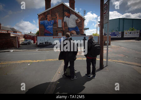 Zwei Männer auf einem Wandgemälde des Künstlers Paul Curtis auf die giebelseite eines Hauses in Prenton, Wirral mit zwei Tranmere Rovers Spieler. Das Wandbild ist nur außerhalb des Stadion des Clubs, Prenton Park entfernt. Tranmere Rovers gewonnen Förderung zu EFL League 2 aus der Nationalen Liga über einen Play-off in der Saison 2017-8 und kehrte 12 Monate später, am 25. Mai zum Wembley Newport County für einen Platz in der EFL-Liga eine zu Gesicht. Stockfoto