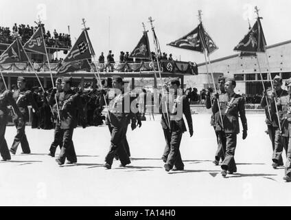 Foto von einer Gruppe von Deutschen Legionäre mit Standards der verschiedenen Einheiten der Legion Condor während einer Siegesparade für General Francisco Franco am Flughafen Barajas, Madrid, nach der Invasion der Spanischen Truppen in der Stadt am 28. März 1939. Im Hintergrund, der Terminal des Flughafens, die bei einem VIP-Ständer gedreht wurde. Stockfoto