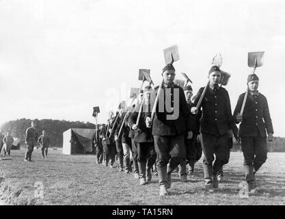 Mitglieder der Freiwilliger Arbeitsdienst - Freiwillige Arbeit Service (FAD) gehen mit ihren Schaufeln und in Uniform aus ihrer Arbeit Camp zum Arbeitsplatz beim Singen. Stockfoto