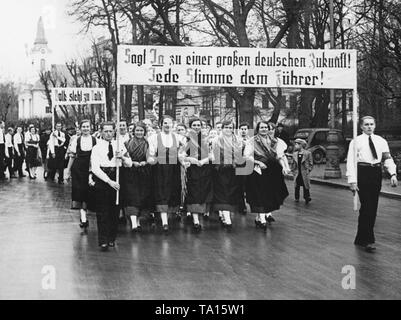 Eine Gruppe von Sudetendeutschen Frauen in traditionellen Kostümen auf dem Weg zum polling Lage. In die Sudetendeutsche Nachwahlen, abgegebenen Stimmen über die Annexion des Sudetenlandes an das Deutsche Reich. Auf den Plakaten: 'Sag Ja zu einem großen deutschen Zukunft! Jeder Stimme für den Führer! ' Und 'Volk steht um Menschen!". Stockfoto