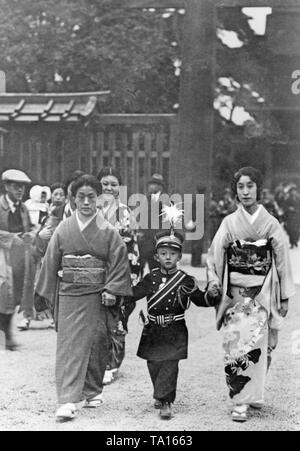 Zwei Frauen und ein Junge zum Gebet ist ein Neues Jahr im Heiligtum von Kaiser Meiji in Tokio. Der Junge ist als Soldat verkleidet. Stockfoto