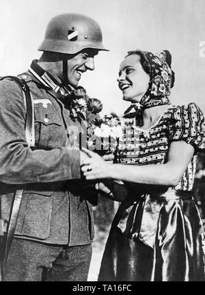 März - im von deutschen Truppen während der Annexion Österreichs an das Deutsche Reich. Ein deutscher Soldat erhält Blumen von einer jungen Frau. Stockfoto