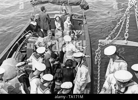 Foto von einer Gruppe deutscher Flüchtlinge während des Spanischen Bürgerkriegs in einem beiboot Der Schwere Kreuzer 'Deutschland' auf einer Reede aus Valencia. Eine Gruppe von Matrosen und ein Offizier helfen Menschen an Bord 'Deutschland' kommen. 'Deutschland' brachten die Flüchtlinge nach Girona, wo Sie durch die Dampfer der NS-Organisation "Kraft durch Freude" ('Stärke durch Freude'), Monte Sarmiento (1924 gestartet, Monte-Klasse, 1942 versenkt) aufgenommen wurden. Stockfoto