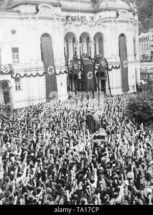 Blick auf den Theaterplatz (Theaterplatz) heute in Karlsbad (Karlovy Vary) am 4. Oktober 1938, während Adolf Hitler ist eine Rede während der Besetzung des Sudetenlandes. Hitler steht auf dem Balkon. In der Mitte der Menschenmenge ist eine Kamera Crew (Wochenschau) auf dem Dach eines Autos. Stockfoto
