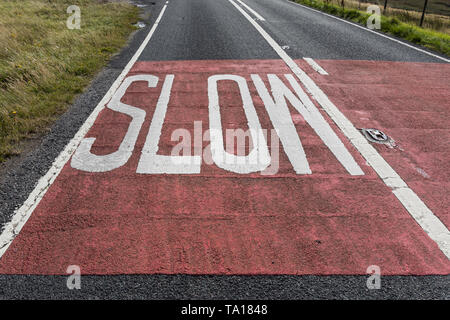 Warnschild auf der Straße in England geschrieben. Langsam signalisieren Stockfoto
