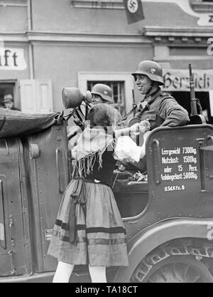 Ein Mädchen steckt eine Blume auf die Uniform eines Soldaten am 3. Oktober 1938, in Grottau (heute Hrádek nad Nisou). Die soldaten Sitzen in einer Zugmaschine Sdkfz. (Buessing AG). Stockfoto