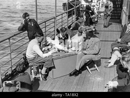 Die Passagiere nehmen teil an einer Kreuzfahrt der Nationalsozialistischen Organisation "Kraft durch Freude" (Kraft durch Freude). Die Touristen spielen Skat auf dem Deck des Schiffes 'Der Deutsche'. Das Ziel der Reise ist der portugiesischen Insel Madeira. Stockfoto