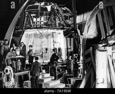 Diese Aufnahme zeigt den Regisseur Fritz Lang (sitzend am Schreibtisch) während der Dreharbeiten zu dem Science-Fiction-Film "Frau im Mond". Die Landschaft ist eine Rakete Kapsel für Piloten und wurde nach den Entwürfen des Beraters Prof. Hermann Oberth gebaut. Stockfoto