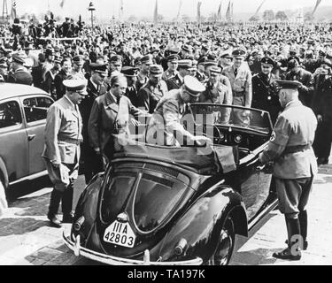 Adolf Hitler bekommt in einem Prototyp des VW Käfer Cabrio. Hinter Hitler, der Designer des Käfers, Prof. Ferdinand Porsche. Links von Porsche ist der Stabschef der SA Viktor Lutze, die Reich Führer der NSDAP Robert Ley, Adolf Huehnlein und Alfred Rosenberg. Stockfoto