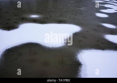 Die Risse und angesammelten Schnee auf der Oberfläche des gefrorenen See. Stockfoto