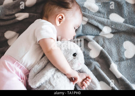 Cute Baby Mädchen schlafen mit Bunny Spielzeug im Bett Nahaufnahme. Guten Morgen. Ansicht von oben. Stockfoto