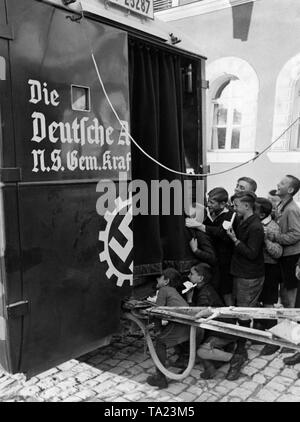 Undatiertes Foto von einem Theater Auto der NS-Organisation "Kraft durch Freude" ('Stärke durch Freude') mit einem eingebauten Filmprojektion, neugierige Kinder betrachten. Stockfoto