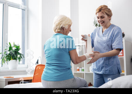 Schön gealterte Frau an ihren bandagierten Hand suchen Stockfoto