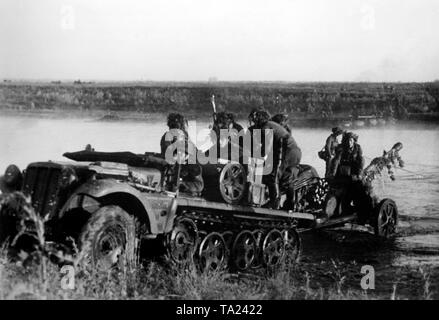 Deutsche Infanteristen Kreuz ein kleiner Fluss im südlichen Abschnitt der Ostfront in der Nähe von Schtschigry mit einem leichten Zugkraftwagen 1t (SdKfz. 10) und eine gezogene Pak 5 cm 38. Die Helme der Soldaten und die Waffe mit Zweigen getarnt sind. kriegsberichterstatter: Kirchner. Stockfoto