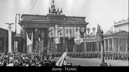 Foto der Pariser Platz mit dem Brandenburger Tor im Hintergrund während der Parade anlässlich der Rückkehr der Legion Condor im Spanischen Bürgerkrieg am 6. Juni 1939. Im Vordergrund, Fußgänger auf der Straße. Die Soldaten marschieren in der Unter den Linden Straße Richtung Osten zum Lustgarten. Auf der rechten Seite, ein Omnibus stoppen. Stockfoto