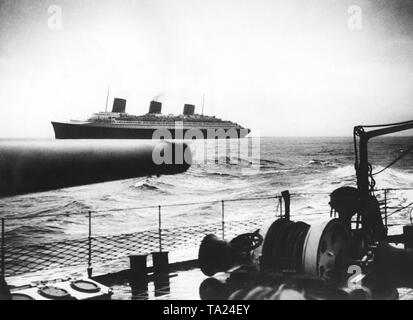 Ein Schlachtschiff erfüllt die französischen Ozean Liner "Normandie" auf See. Stockfoto