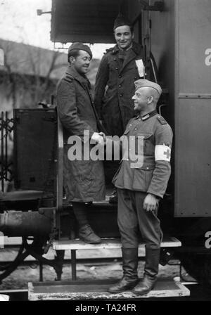 Französische Kriegsgefangene, die aus gesundheitlichen Gründen aus der Gefangenschaft entlassen wurden und nun abgeschoben werden, kommen in Chalon-sur-Saone an der deutsch-französischen Demarkationslinien. Ein deutscher Sanitäter schüttelt Hände hier in der Verabschiedung. Auf der Brust ist deutlich sichtbar das SA-Sportabzeichen. Stockfoto