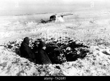 Zwei Soldaten mit einem Maschinengewehr 34 ein Gewehr 98 (Mauser Modell 98) sichern eine 7,5 cm Flak aus einer Schlacht. Foto der Propaganda Firma (PK): kriegsberichterstatter Schoedel. Stockfoto