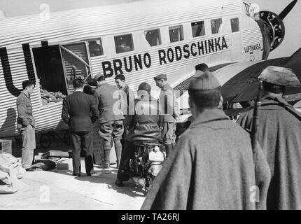 Foto eines deutschen Junkers Ju 52 der Deutschen Lufthansa AG 1939 am Flughafen Salamanca, Kastilien und Leon, Spanien. Das Flugzeug trägt den Namen "Bruno Rodschinka'. Es wird gerade geladen. Im Vordergrund, zwei Polizisten der Guardia Civil. Stockfoto