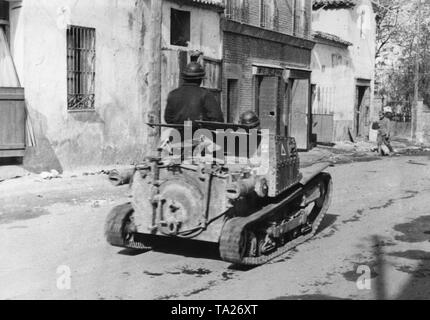 Foto von der Rückseite eines italienischen 2-Mann Tank (L3/33, Carro Veloce 33) des Corpo Truppe Volontarie (CTV), durch die Mitte von Villaverde del Rio, nördlich von Sevilla. Die Besatzung trägt Leder Helme. Stockfoto