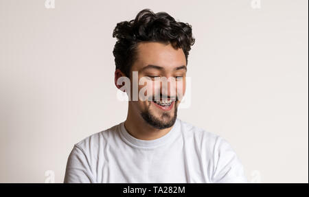 Porträt eines jungen Mannes mit Klammern lächelnd. Ein glücklicher junger Mann mit Klammern auf einem weißen Hintergrund. Stockfoto