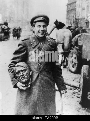 Ein fröhliches Lachen sowjetischen Soldaten trägt eine Bronze Hitlers Kopf als Erinnerung, die er in den Trümmern der zerstörten Reichskanzlei sofort nach dem Ende der Kampfhandlungen gefunden hat. Stockfoto