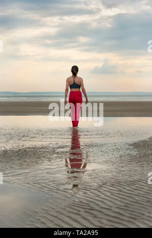 Rückansicht eines sportlichen Frau entlang eine Sandstrand Stockfoto